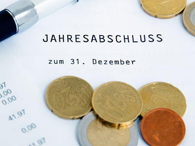Jahresabschluss-Dokument mit Münzen und einem Stift.